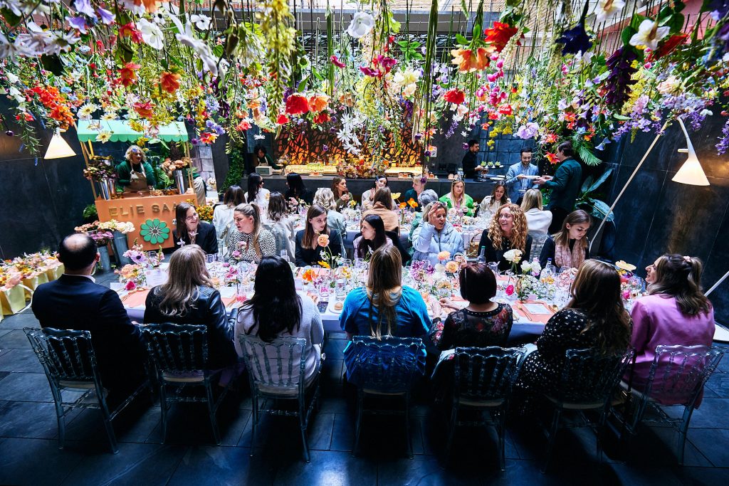 Ladies sat at a table at a fragrance event adorned with flowers