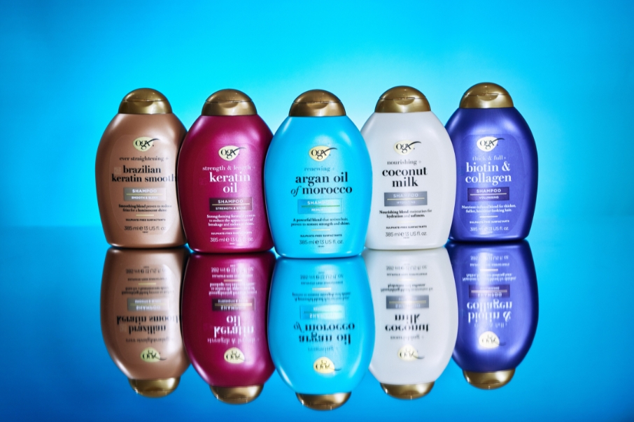 Line of up OGX haircare shampoo bottles against a blue background