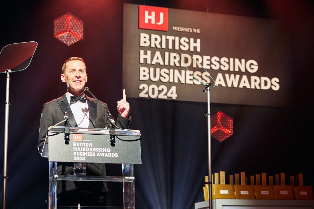 Photo of Scott Mills behind a lectern presenting awards at the British Hairdressing Business Awards 2024