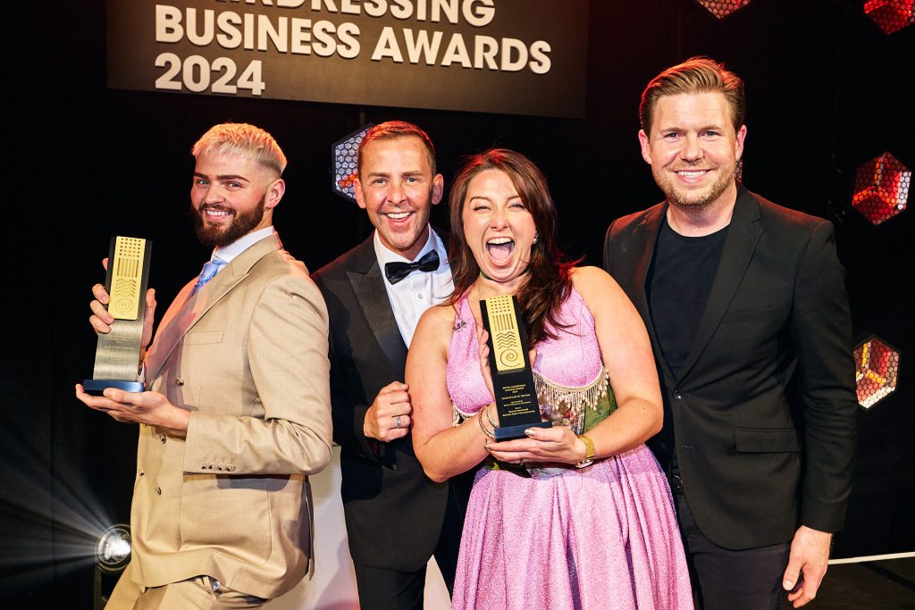 Woman in pink dress smiling with an award at the British Hairdressing Business Awerds