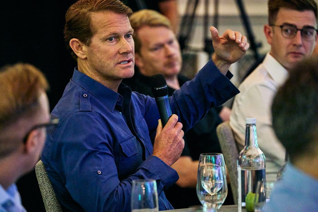 Image of a man in the audience of a conference with a microphone asking a question