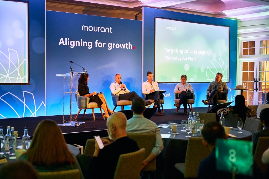 A row of panellists on stage at a conference for Mourant