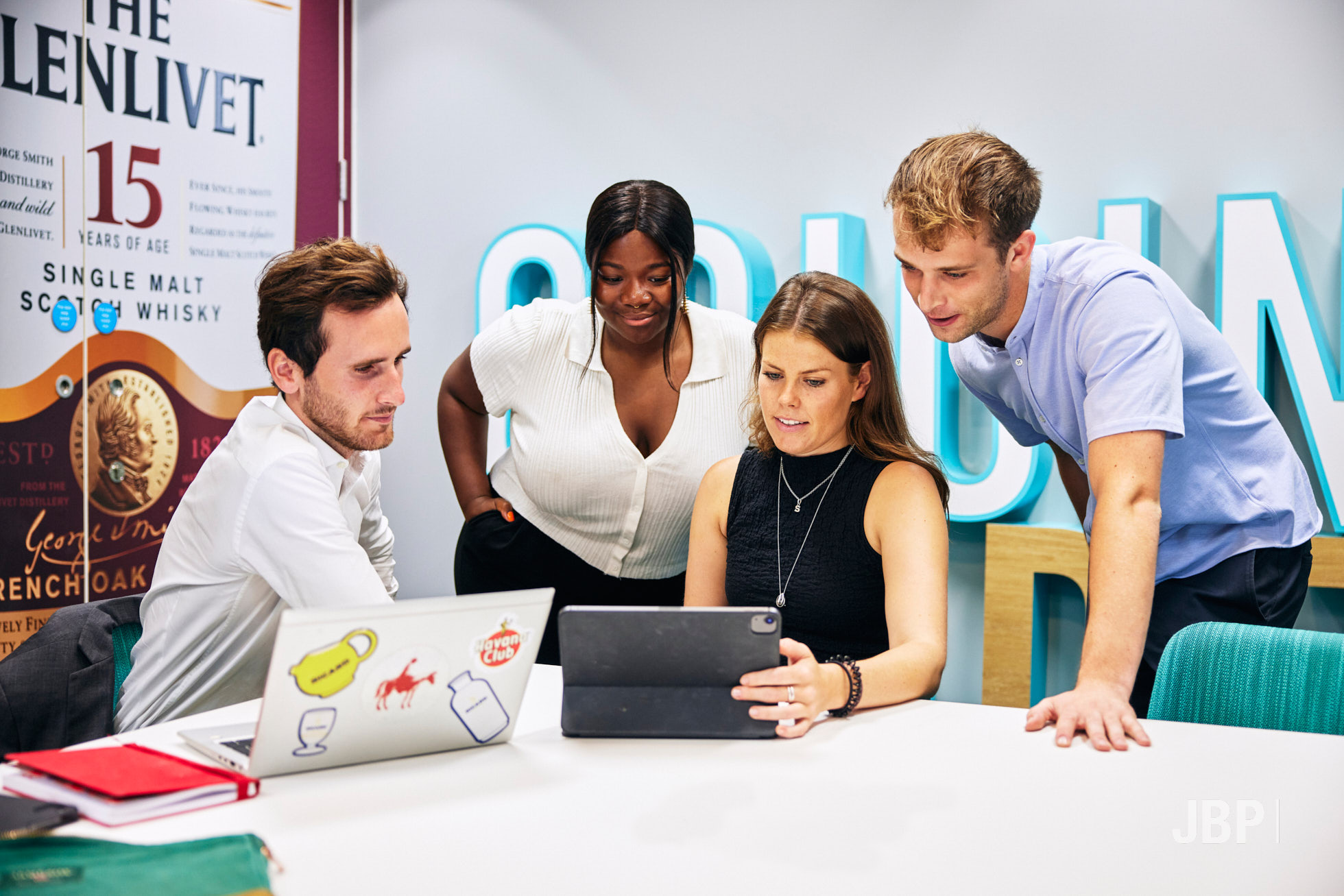 Corporate lifestyle photography showing a two women and two men around a table looking at two laptops